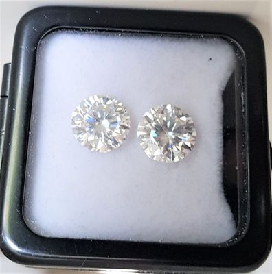 two diamond stud earrings in a black box on a white surface
