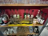 bottles and glasses on a shelf in a room with a red wall