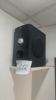 a black speaker sitting on top of a shelf with a note taped to it