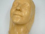 une sculpture jaune représentant une tête d'homme sur une surface blanche