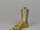 an image of a gold shoe shaped candle holder on a gray surface
