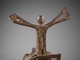 a bronze sculpture of a man sitting on top of a wheel