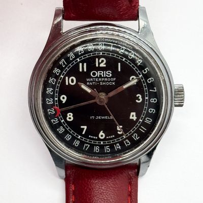 a wrist watch with a black dial on a red leather strap