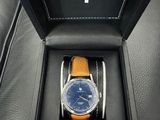 une montre dans une boîte noire posée sur un siège en cuir noir