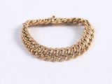 a close up of a gold chain bracelet on a white surface