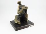 une statue en bronze d'une femme assise sur un rocher