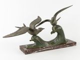 sculpture en bronze représentant deux oiseaux volant au-dessus d'une vague, posée sur un socle en marbre