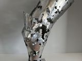 a metal sculpture on a white shelf with a white wall