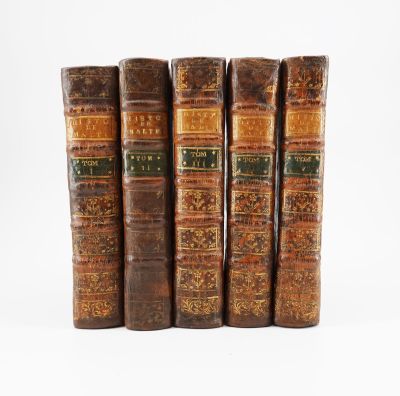 quatre vieux livres posés l'un sur l'autre sur une surface blanche