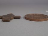 a small wooden cross next to a penny on a table