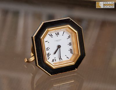 une horloge noire et dorée posée sur une table en verre