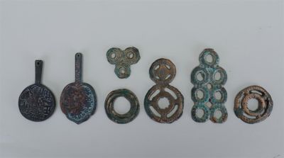 un ensemble de cinq objets métalliques anciens posés sur une surface blanche