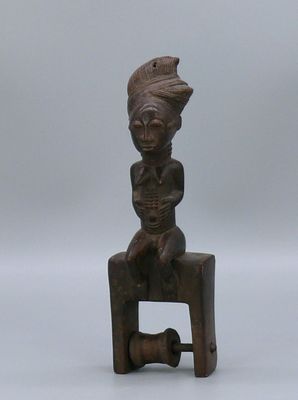 une petite statue en bois représentant une femme assise sur un tabouret