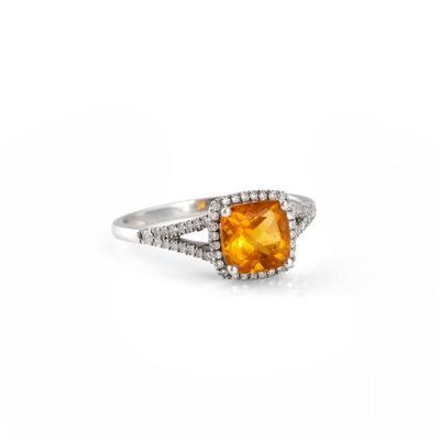 a close up of a ring with an orange stone surrounded by diamonds