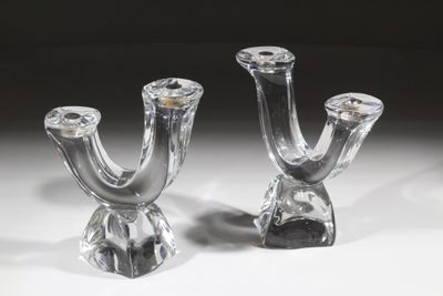 une paire de bougeoirs en verre transparent posés sur une surface blanche