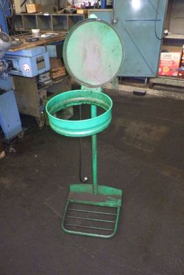 une poubelle verte posée sur un support dans un garage