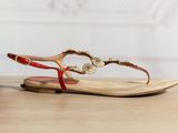 La femme porte une paire de sandales rouges posées sur une table en bois.