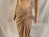 une photo d'un mannequin vêtu d'une robe beige, posé sur un pied de mannequin