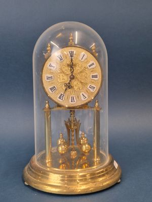 une horloge dorée sous un dôme en verre, sur fond bleu