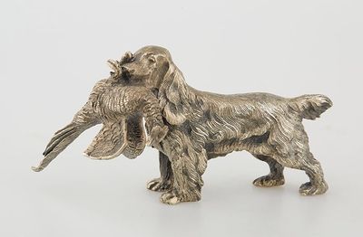 an antique silver dog figurine with a bird in it ' s mouth