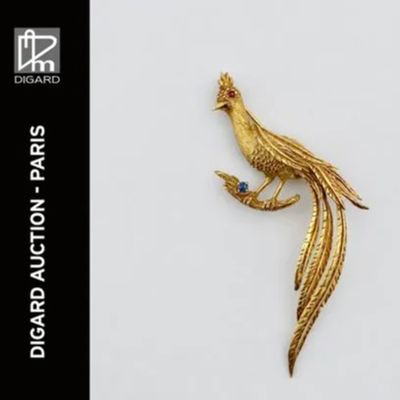 une image représentant une broche en forme d'oiseau en or, avec une pierre bleue dans le bec