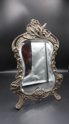 a silver mirror sitting on top of a black table