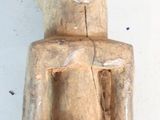 une statue en bois représentant un homme assis sur une surface blanche