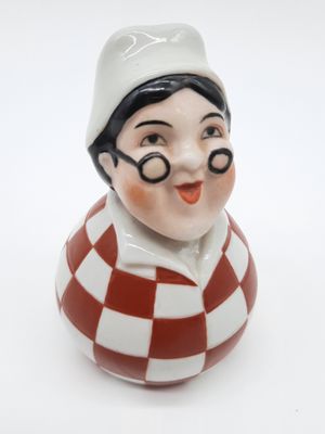 une figurine en céramique représentant un garçon portant des lunettes et un chapeau