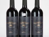 trois bouteilles de vin rouge posées sur une table blanche