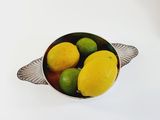 a bowl of lemons and limes sitting on a table