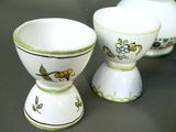 two white cups with green designs on them on a table