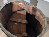 a large wooden bucket sitting on the floor next to a white wall