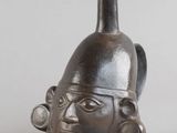 un vase noir orné d'un visage, posé sur une table