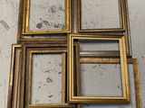 four gold picture frames sitting on top of a white table