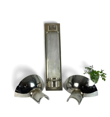 two lights that are on the wall next to a potted plant