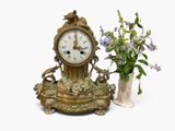 a clock and vase with flowers in it on a table