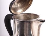 a silver coffee pot with a lid on a table