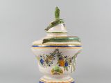 a white and blue vase with a bird sitting on top of it
