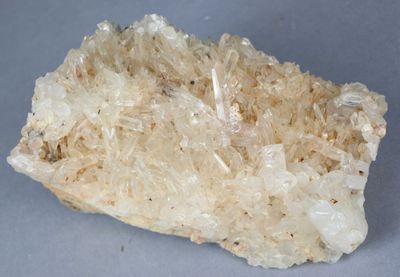 un cristal posé sur une surface grise, avec un petit morceau de roche au milieu
