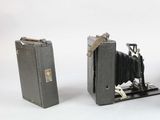 two old cameras sitting next to each other on a white surface