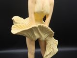 statue d'une femme en maillot de bain jaune posée sur un socle blanc