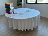a table with a white table cloth and a stack of books on top of it