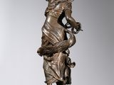 a bronze statue of a woman holding a bird on a pedestal