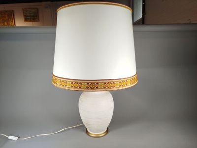 une lampe blanche avec une bordure dorée et un abat-jour blanc