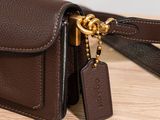 brown leather purse with a gold chain hanging from it ' s side