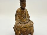 statue en bois représentant un homme assis sur un tabouret, les mains croisées