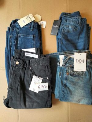 trois paires de jeans pour homme posées sur une boîte en carton