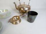 a silver tea pot and a silver cup on a table