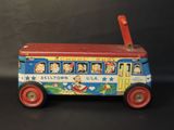 an old fashioned tin toy bus with a red handle on a black surface