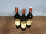 three bottles of wine sitting on top of a wooden table